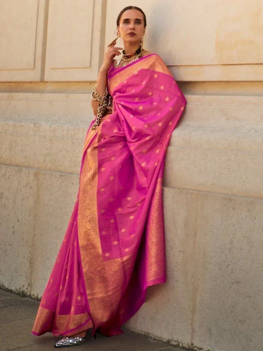 Vibrant pink silk saree with gold zari border and motifs, styled with statement jewelry for ethnic occasions