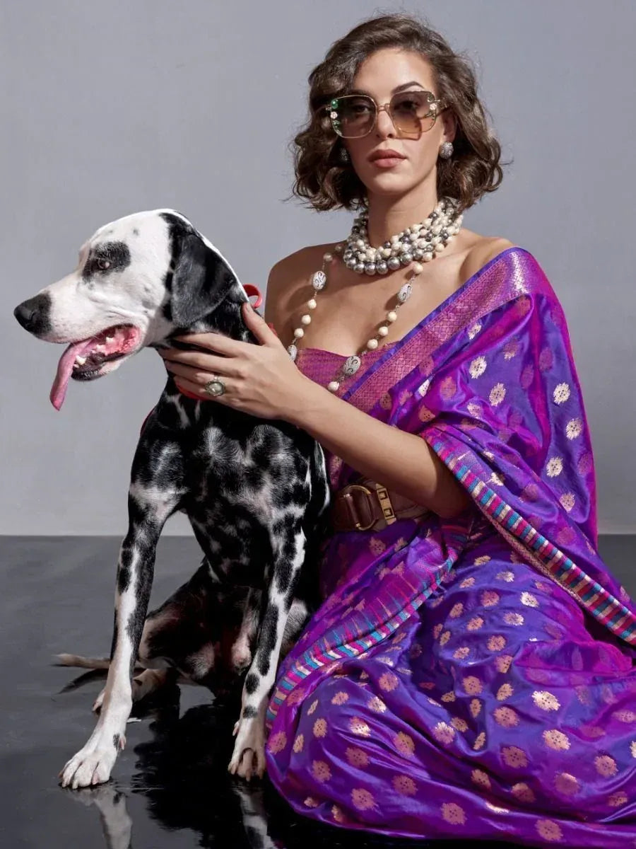Woman in purple designer saree with gold motifs, posing with Dalmatian dog, stylish ethnic wear
