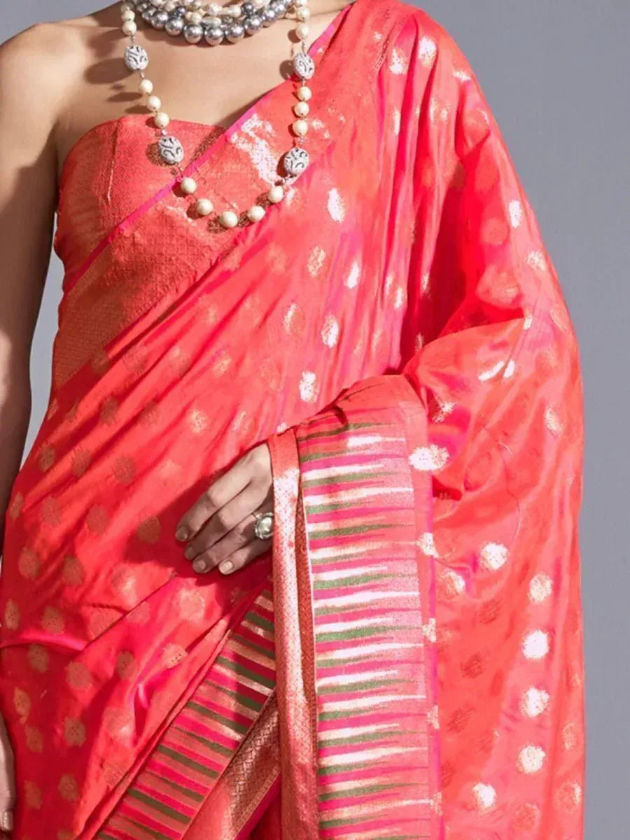 Vibrant coral saree with gold motifs and striped border, paired with pearl necklace for ethnic wear