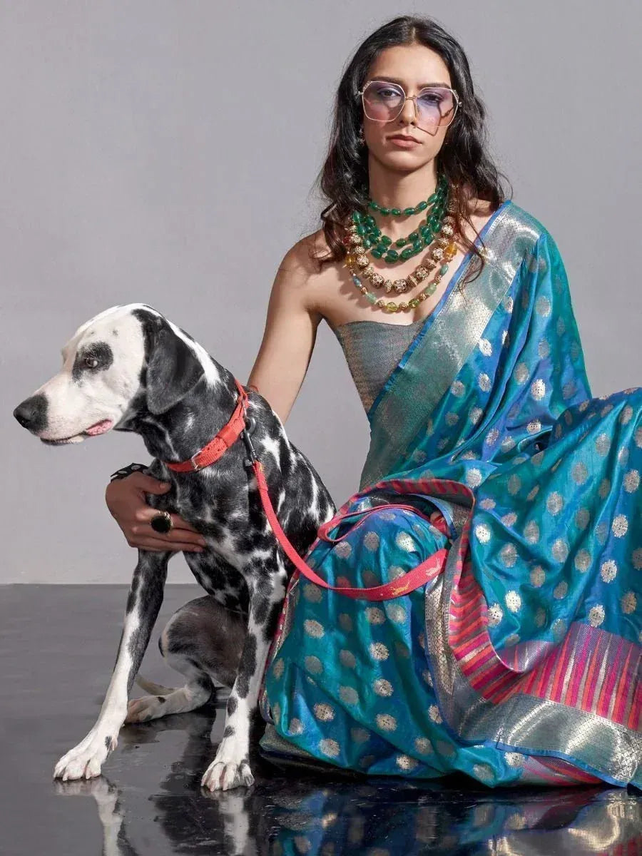 Woman in blue patterned saree with green jewelry posing with Dalmatian dog