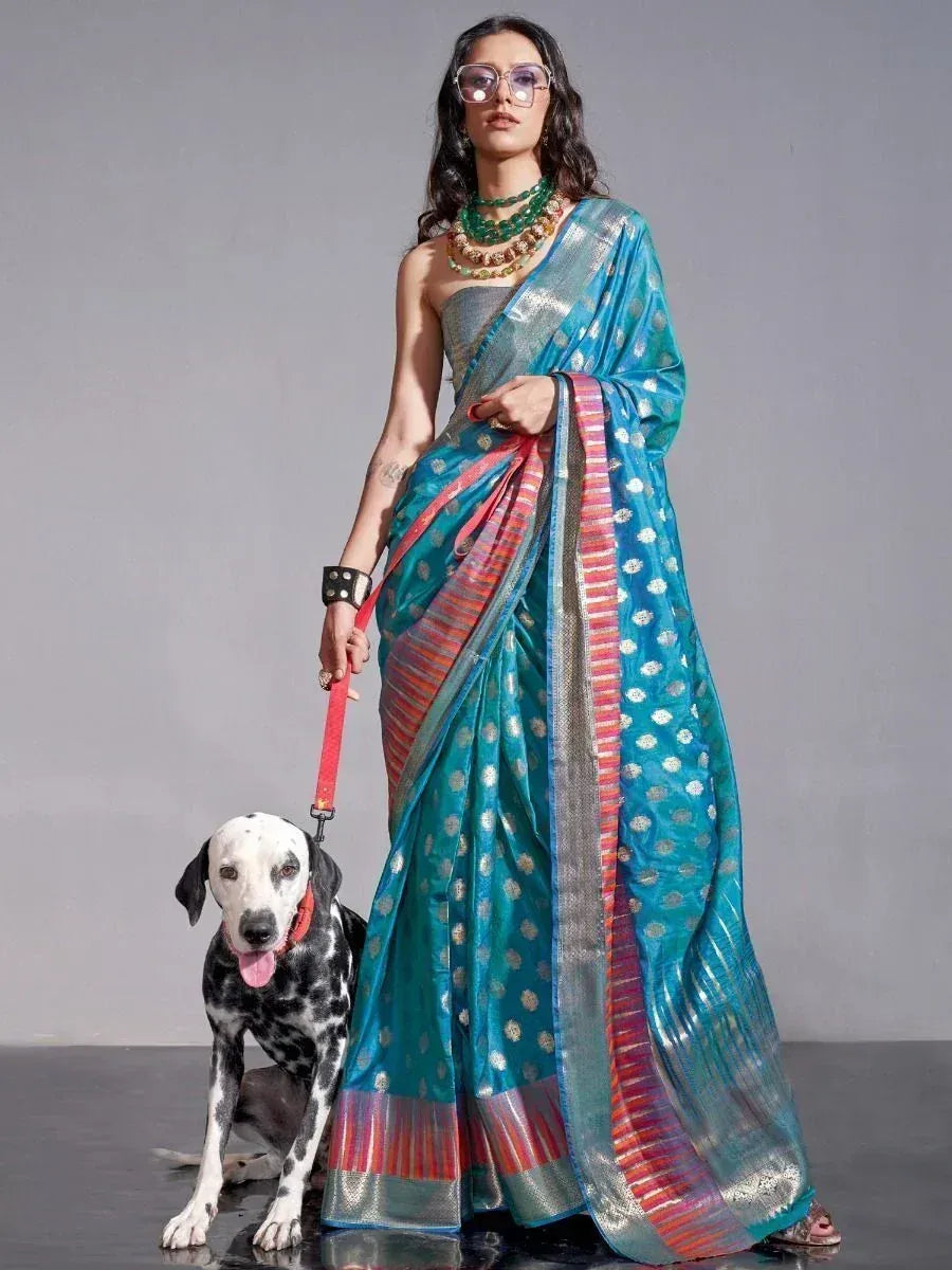 Woman in turquoise designer saree with gold motifs, holding Dalmatian on red leash, styled with green jewelry