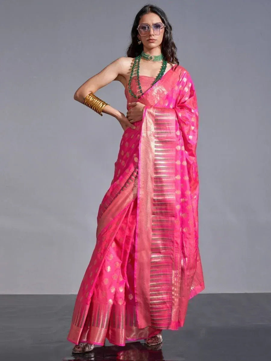 Pink designer saree with gold motifs and border, paired with green jewelry for ethnic wear