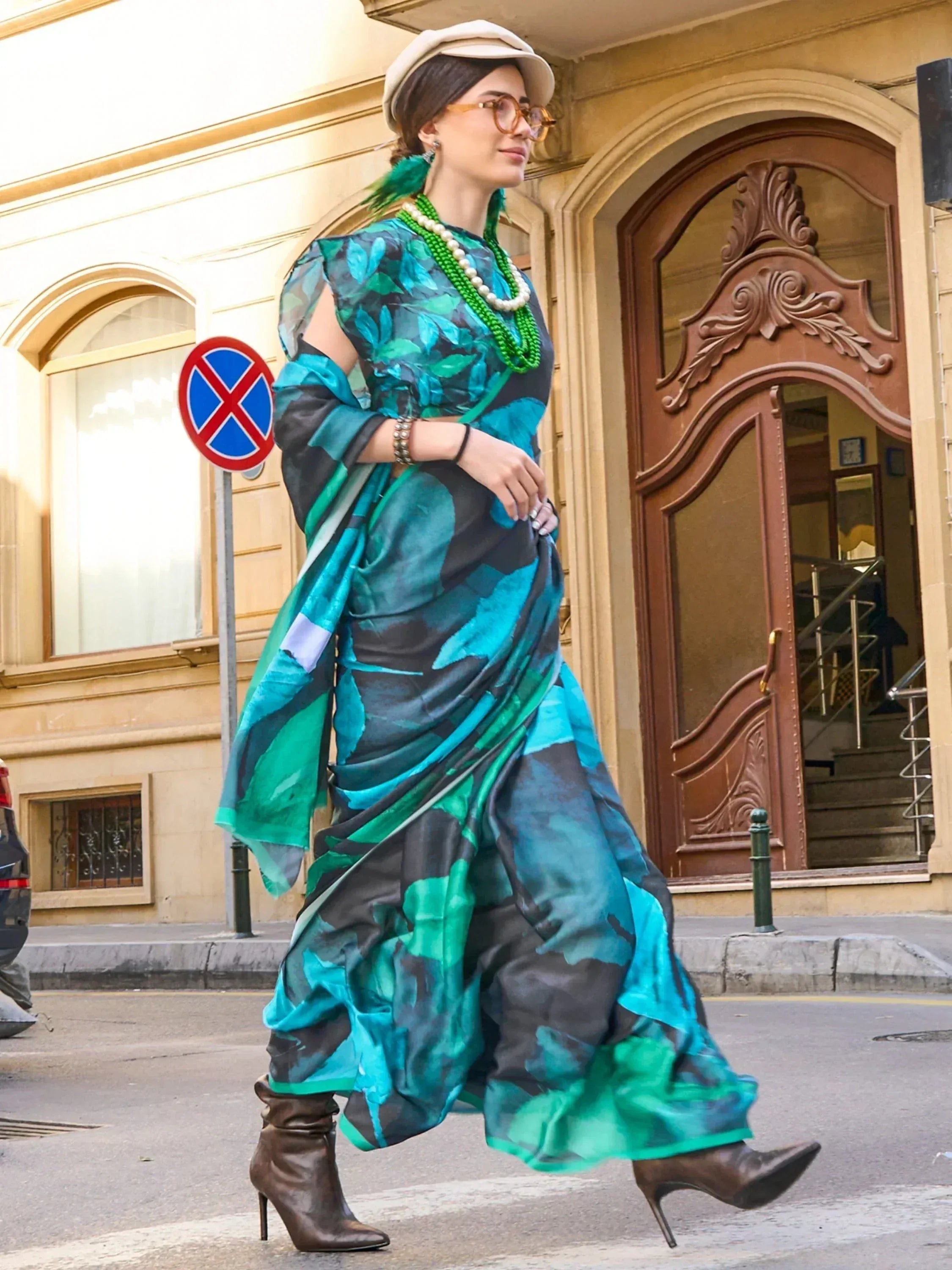 Woman in teal and green printed saree with modern blouse, styled with hat and boots for ethnic fashion