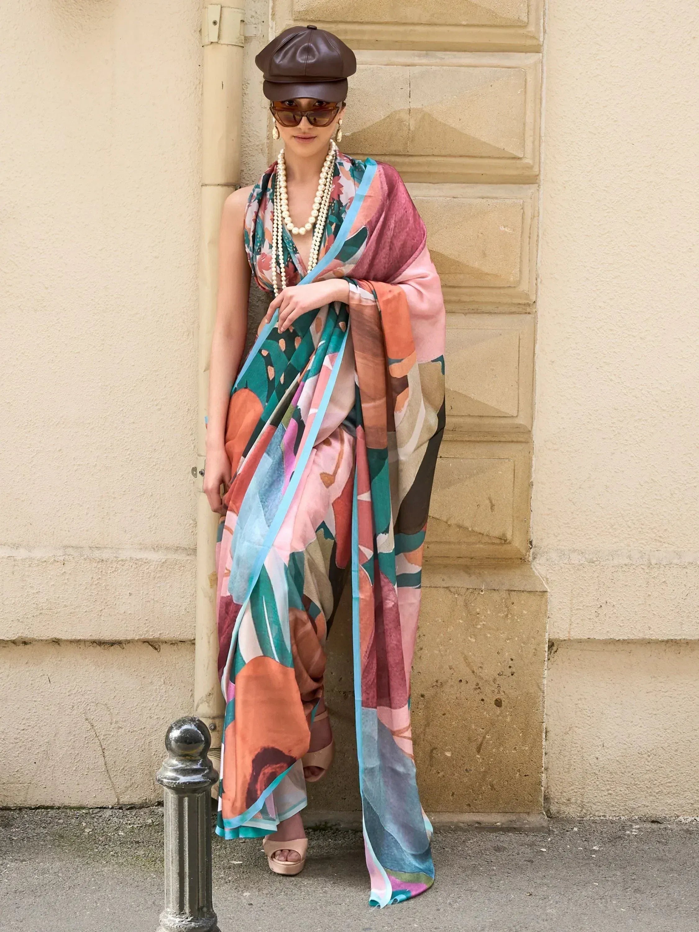 Woman in colorful abstract print ethnic gown with pearl necklace and brown cap, street style