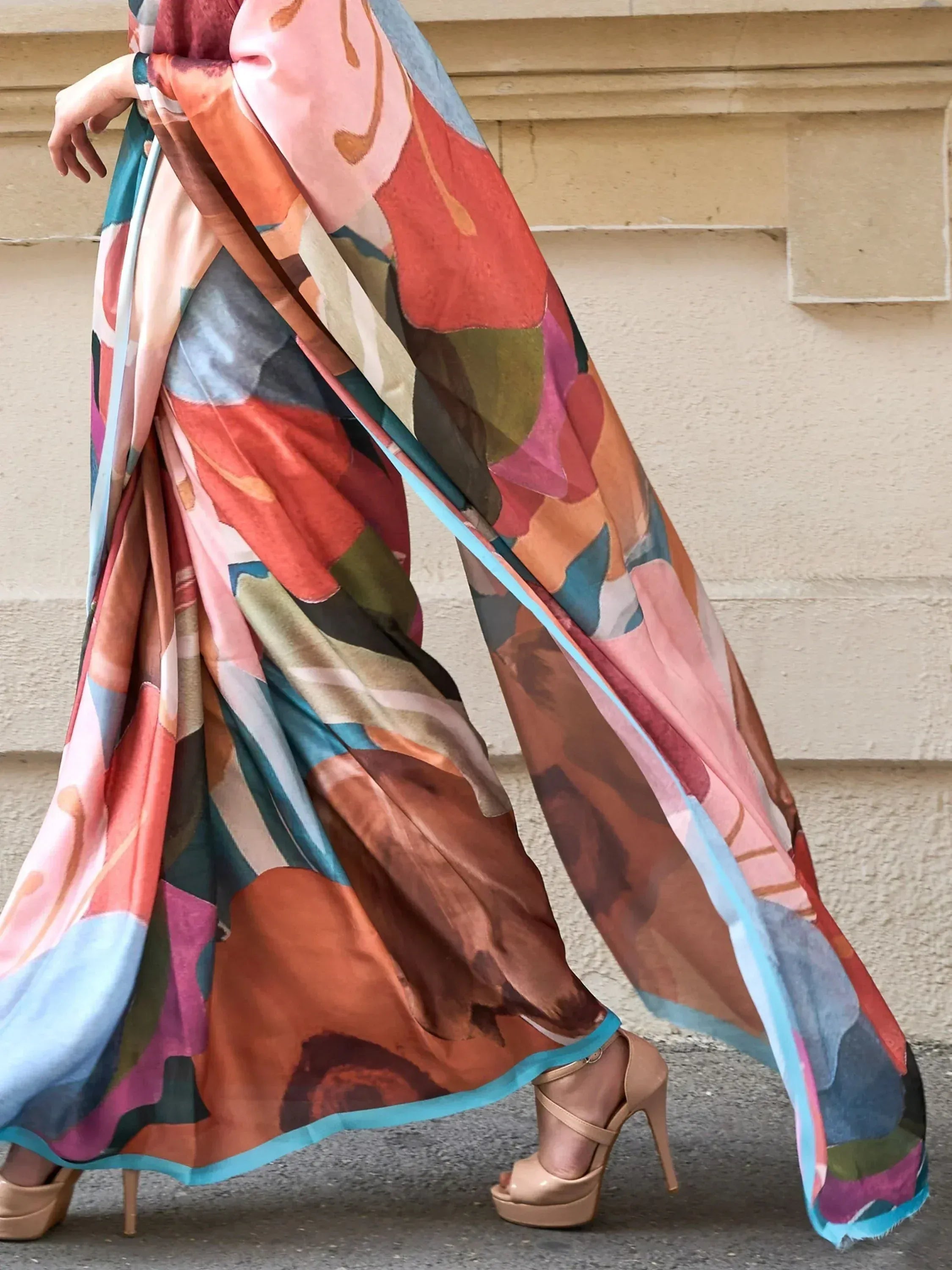 Woman wearing colorful abstract print ethnic gown with flowing fabric and high heels