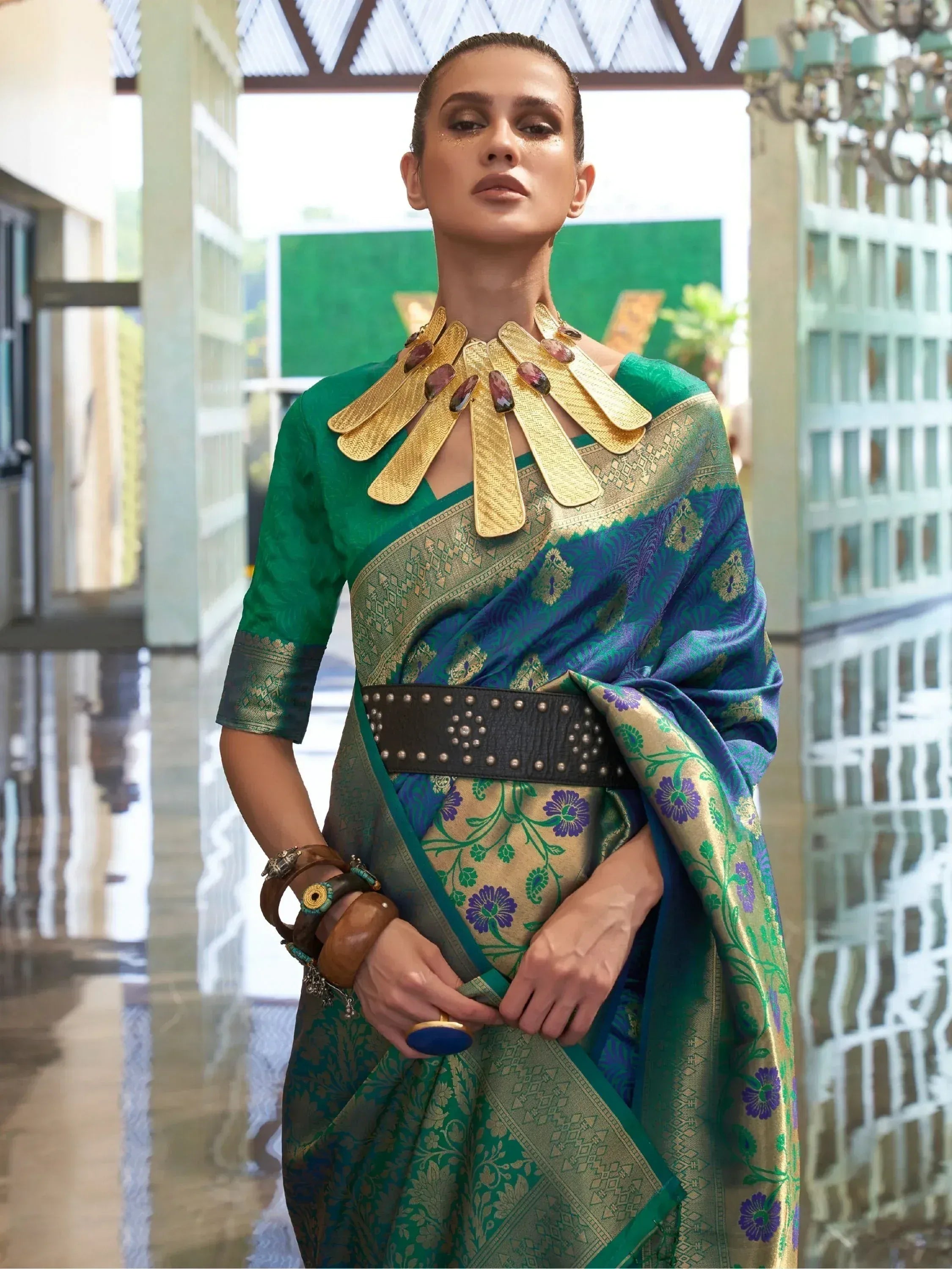 Green and blue designer saree with gold embroidery, statement necklace, and ethnic jewelry for festive occasions