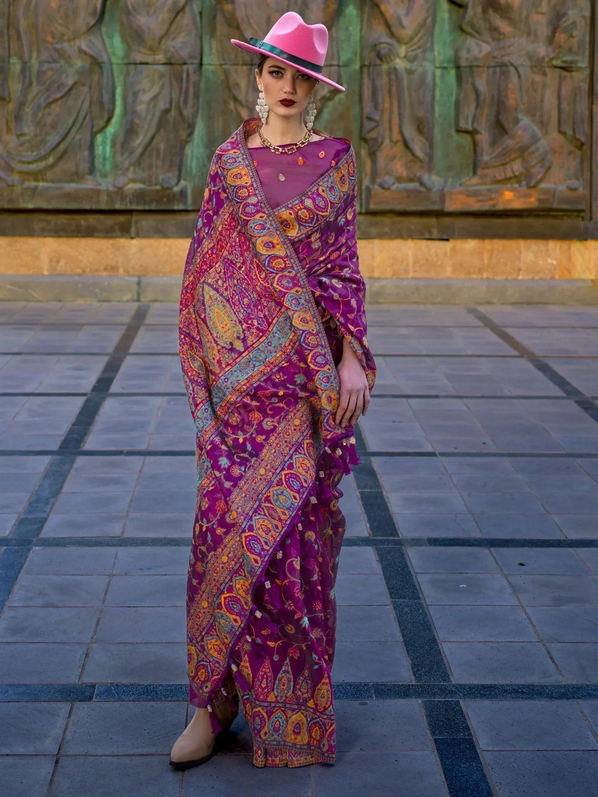 Woman in vibrant purple printed saree with pink hat, ethnic wear for festive occasions