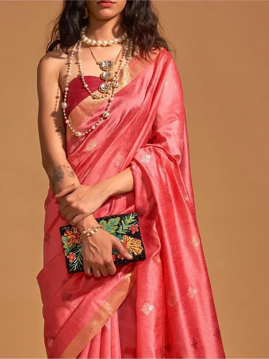 Elegant pink saree with gold border, paired with pearl jewelry and floral clutch for Indian ethnic wear.