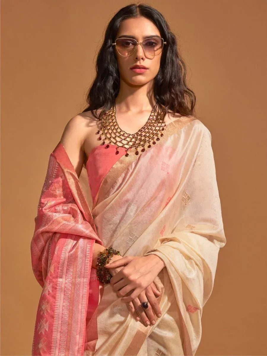 Elegant woman in pink and cream designer saree with gold embroidery, styled with statement jewelry and sunglasses