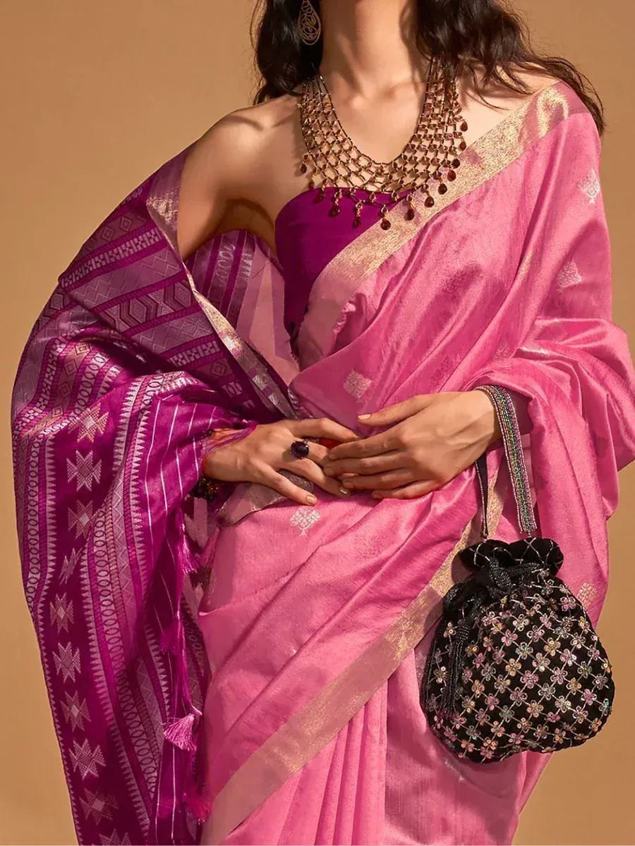 Pink and purple ethnic saree with gold border, paired with statement jewelry and embroidered potli bag