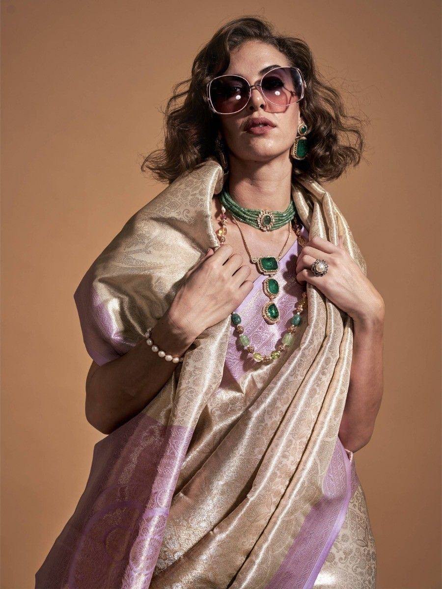 Woman in purple and gold saree with emerald jewelry and sunglasses
