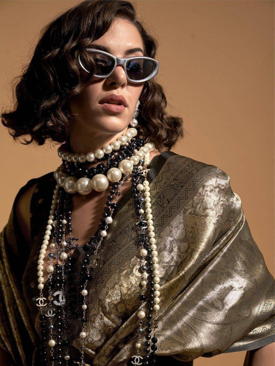 Woman in elegant ethnic saree with layered pearl and black bead necklaces, stylish sunglasses