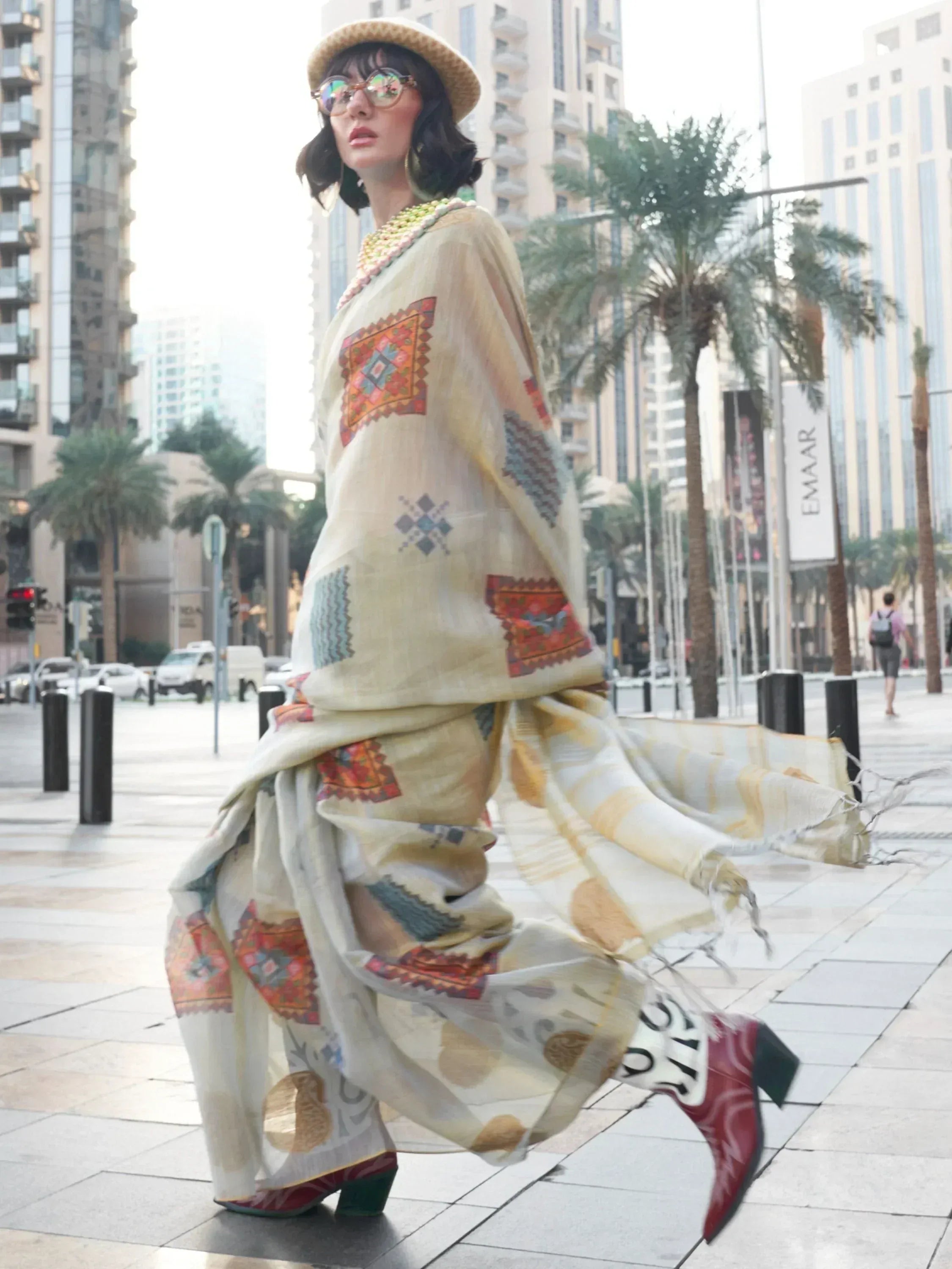 Woman in ethnic printed gown with hat, walking city street, boho fashion, designer Indian wear