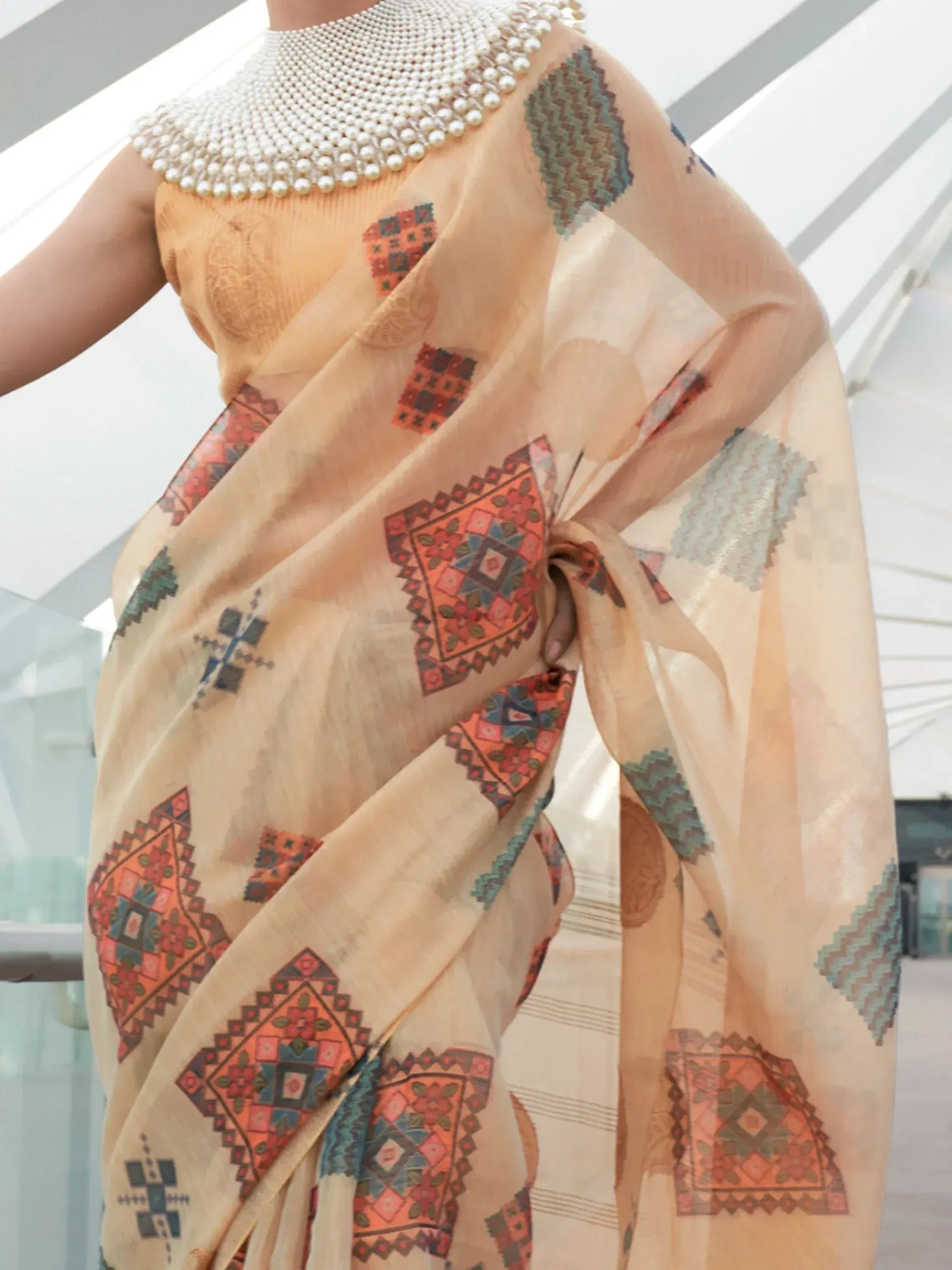 Elegant beige saree with geometric prints and pearl embellished blouse, perfect for Indian ethnic wear