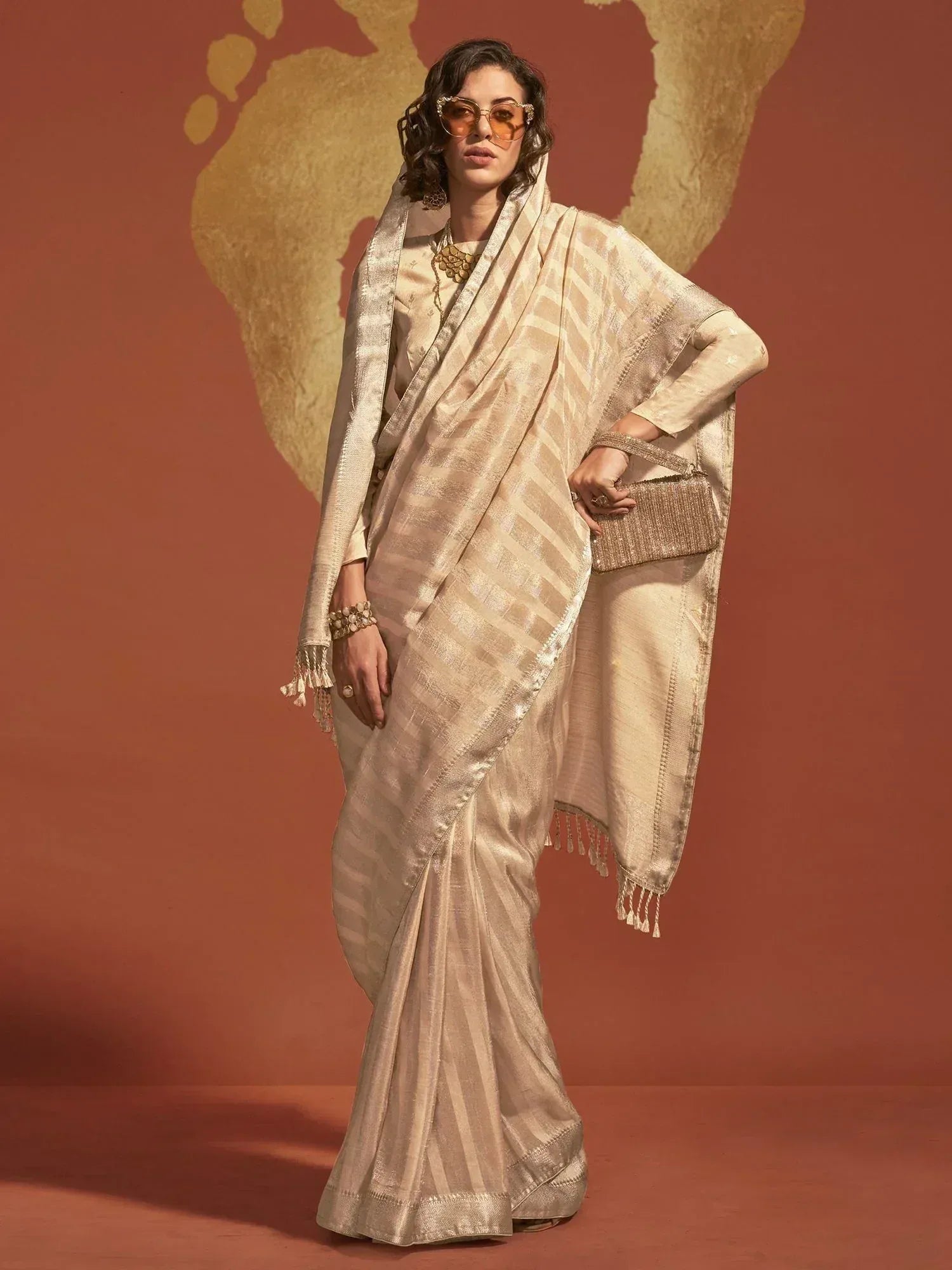 Elegant beige striped saree with matching blouse and dupatta, styled with gold jewelry and sunglasses for a modern ethnic look.