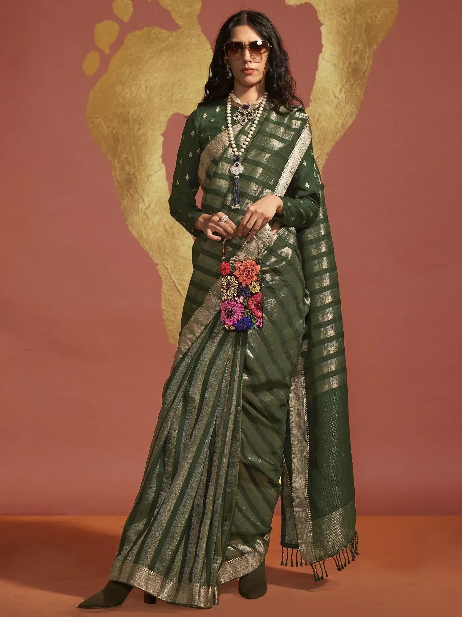 Green striped saree with gold border, floral potli bag, and statement jewelry for ethnic wear
