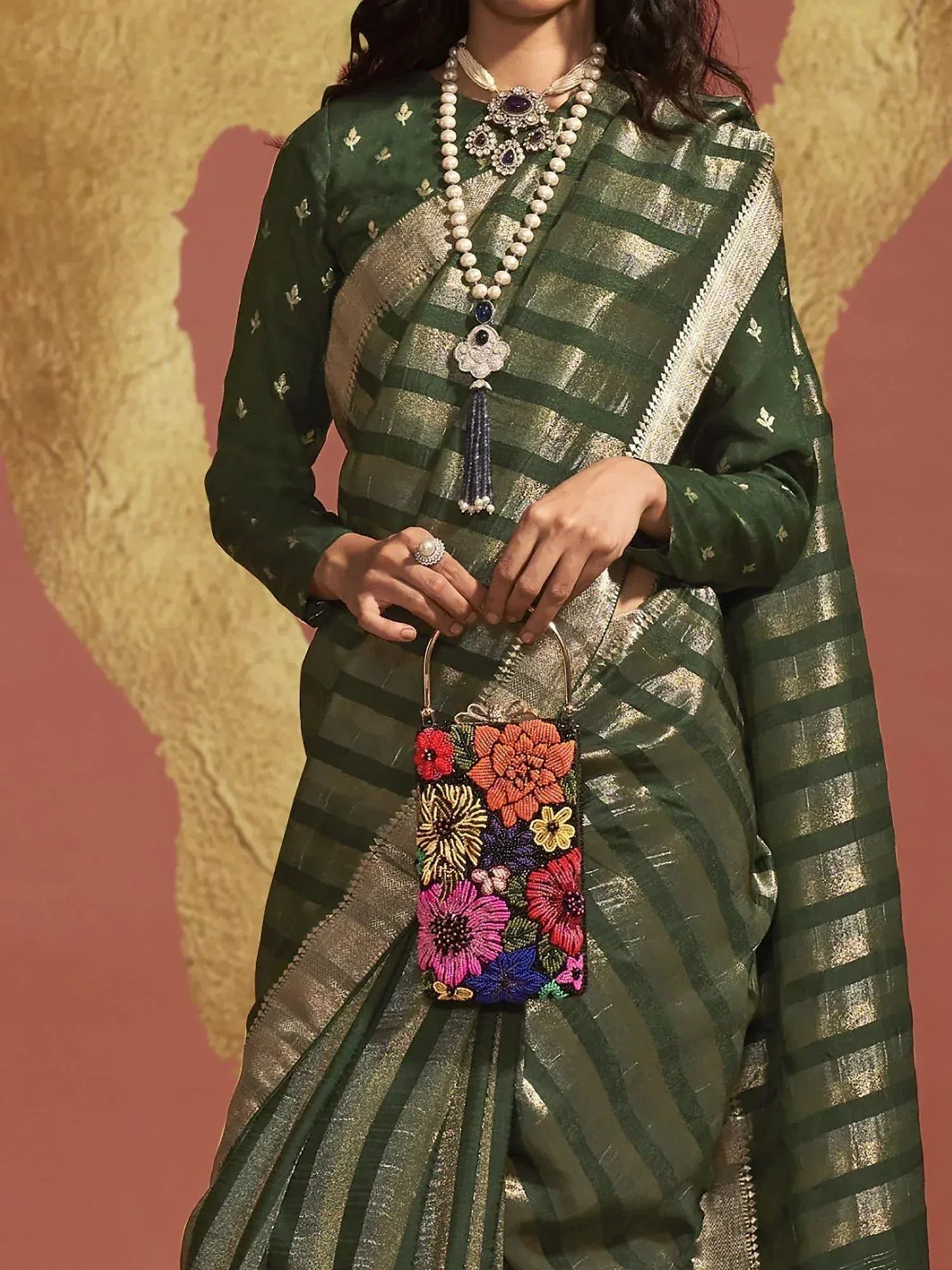 Green and gold striped saree with floral embroidered clutch, pearl necklace, and ethnic jewelry