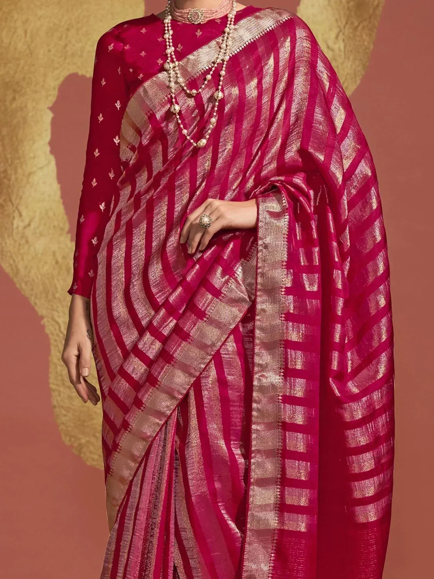 Fuchsia silk saree with gold stripes and blouse, styled with pearl jewelry for Indian ethnic wear