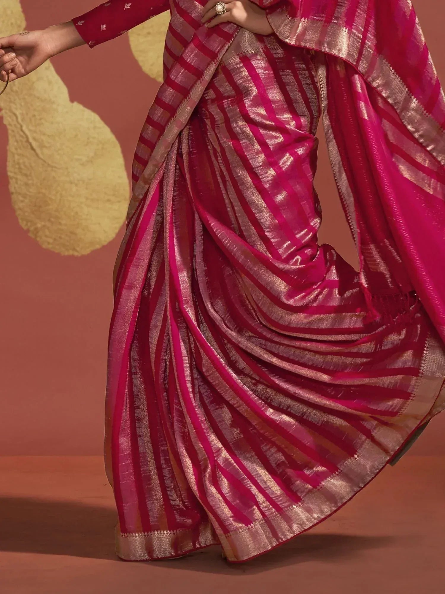 Vibrant pink and gold striped saree with shimmering texture, perfect for ethnic occasions