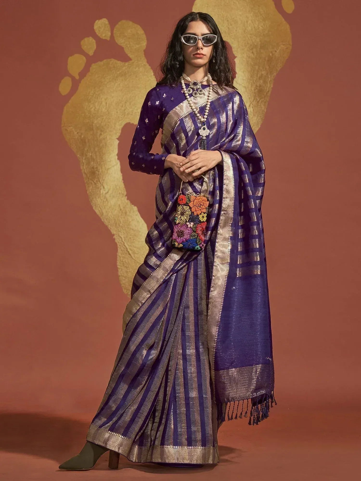 Purple and gold striped saree with embroidered blouse, floral potli bag, and statement jewelry for ethnic wear