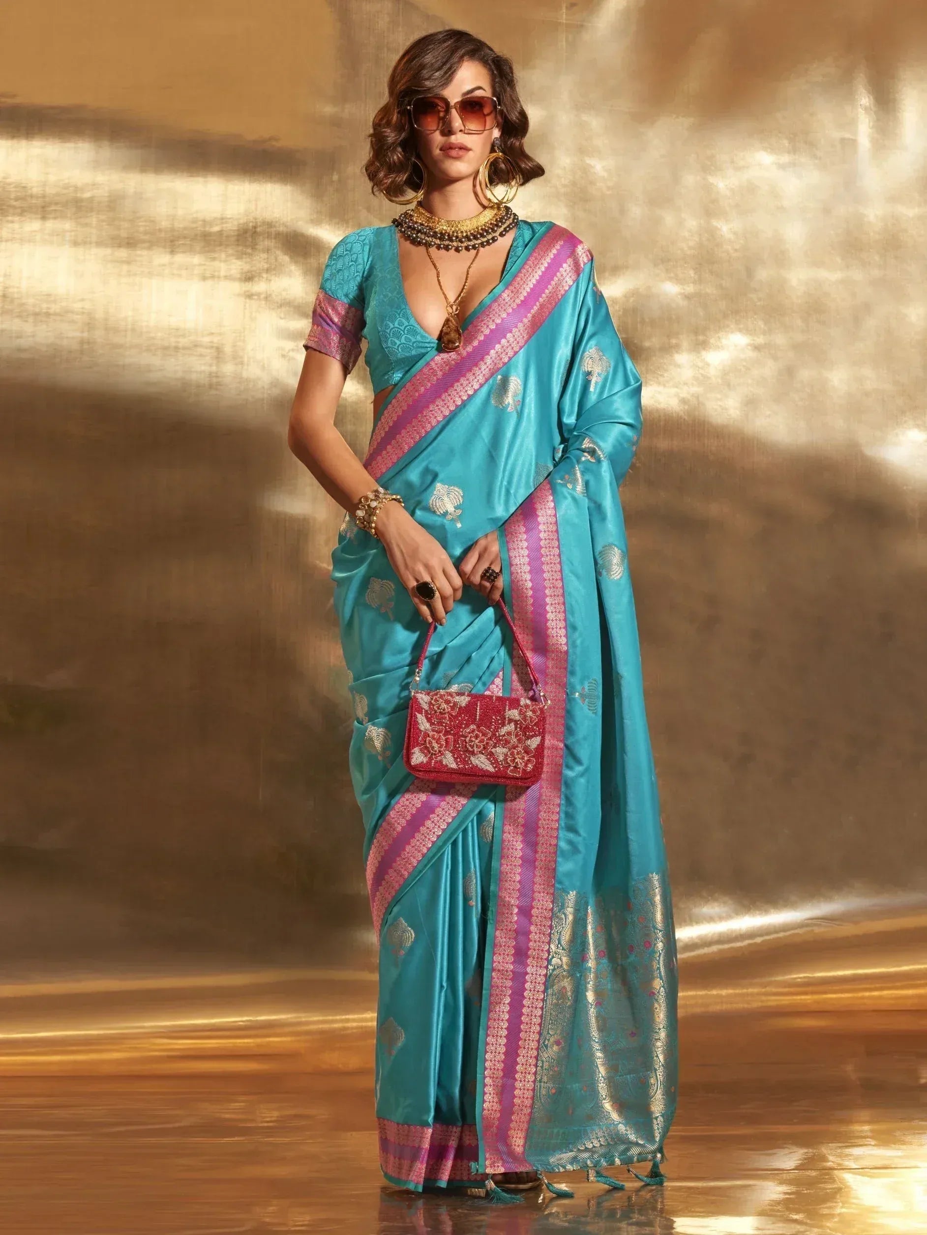 Teal silk saree with pink border and gold motifs, paired with designer blouse and statement jewelry for ethnic wear.