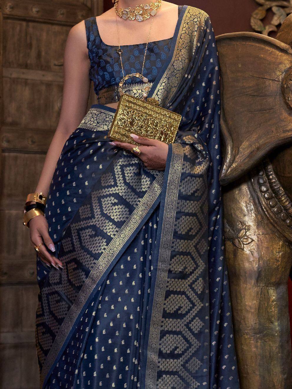 Elegant navy blue saree with gold zari work, paired with matching blouse and ornate jewelry for festive occasions.