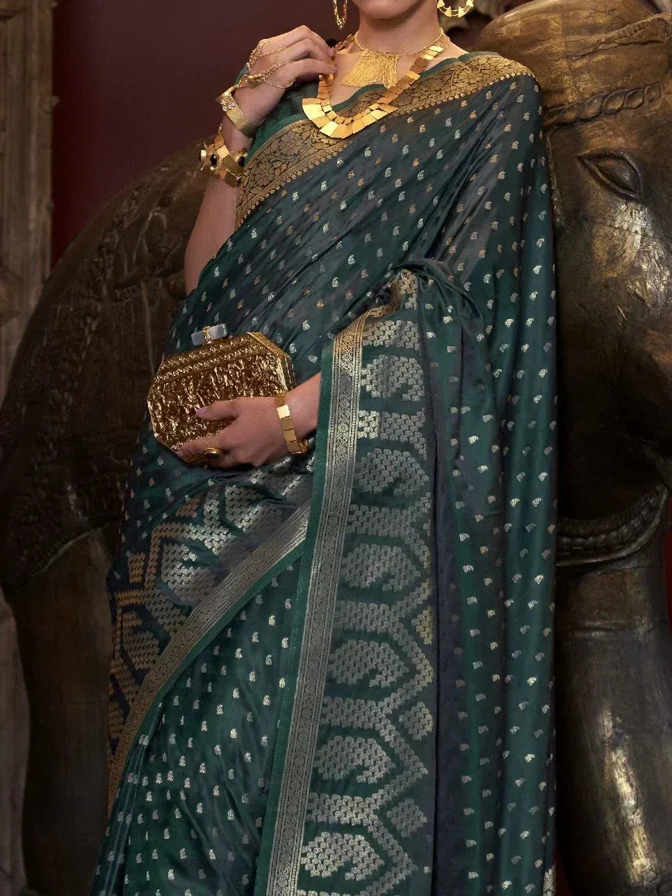 Elegant green ethnic saree with gold motifs, paired with traditional jewelry and clutch, perfect for Indian occasions.