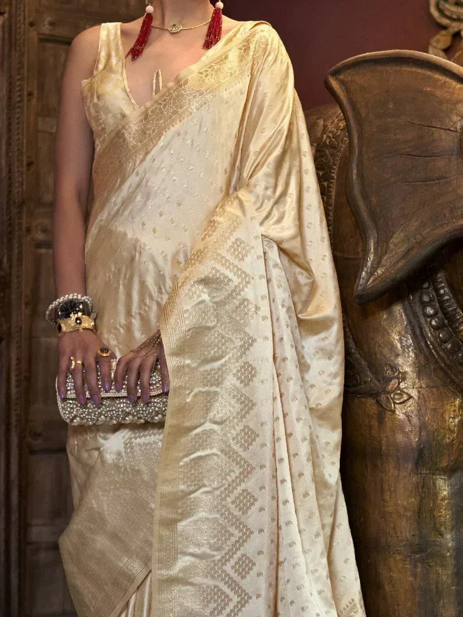 Elegant cream saree with gold embroidery, paired with red tassel necklace and pearl clutch for Indian ethnic wear