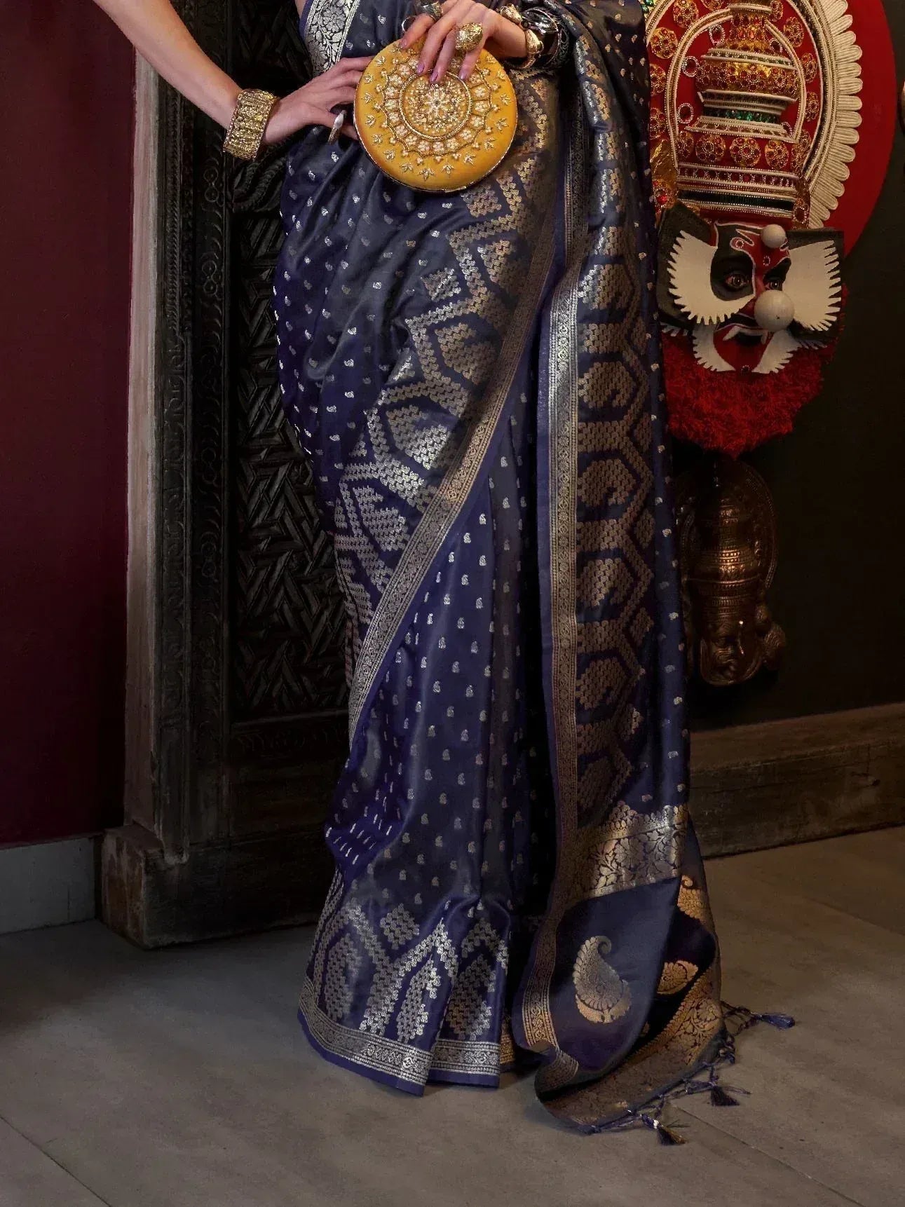 Navy blue designer saree with gold zari work, ethnic blouse, and ornate clutch for Indian occasions