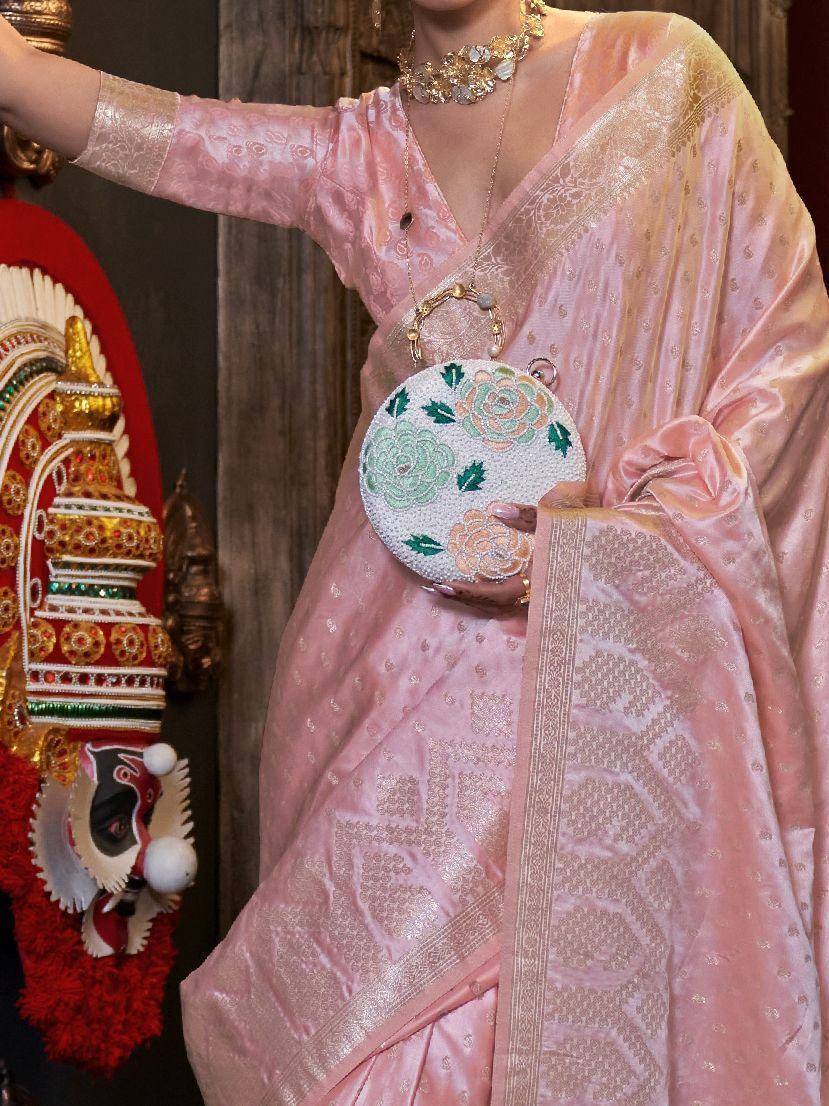 Pink designer saree with gold embroidery, floral clutch, and traditional jewelry for ethnic occasions