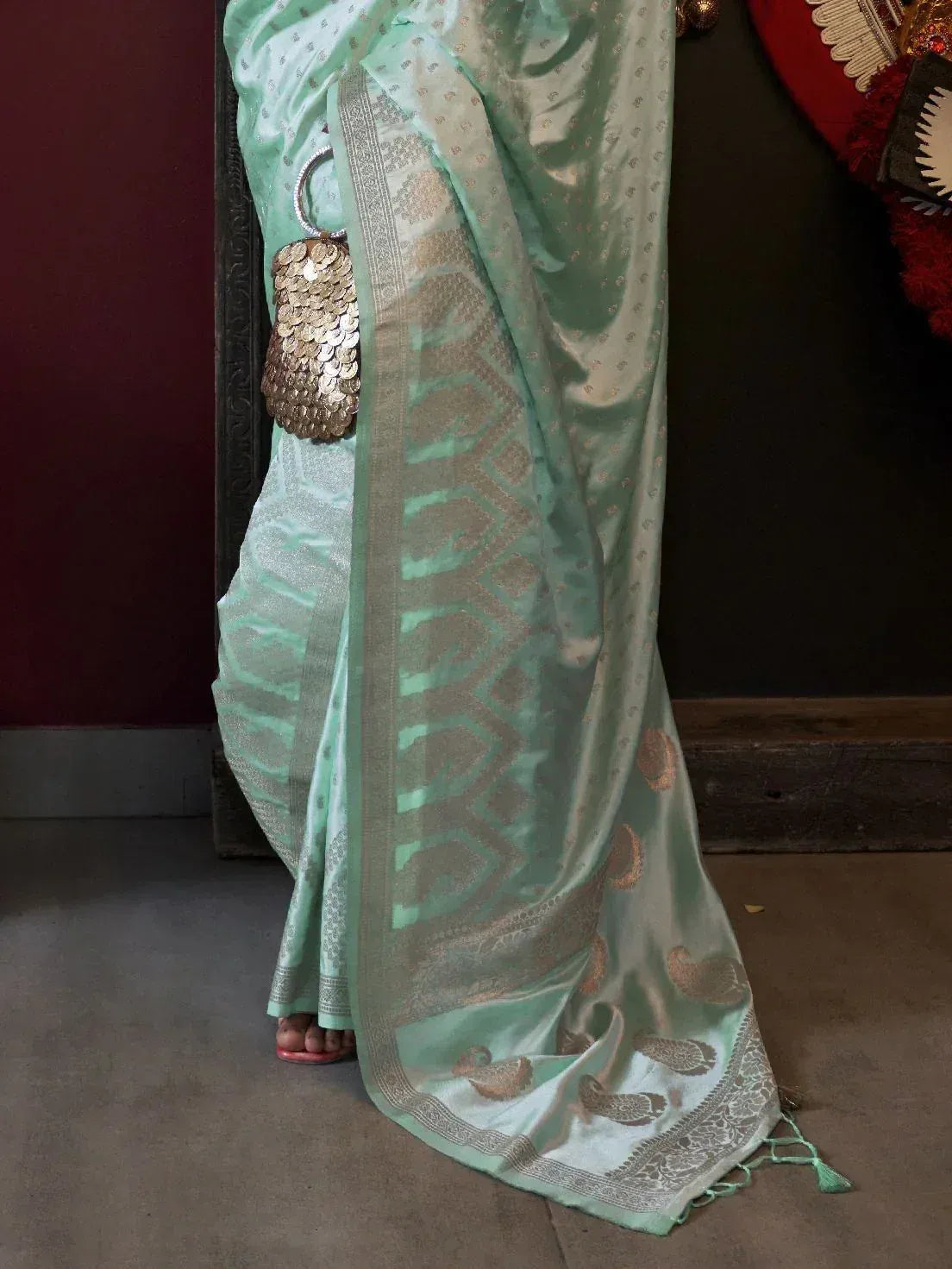 Mint green saree with gold paisley and geometric border, paired with coin clutch, ethnic wear