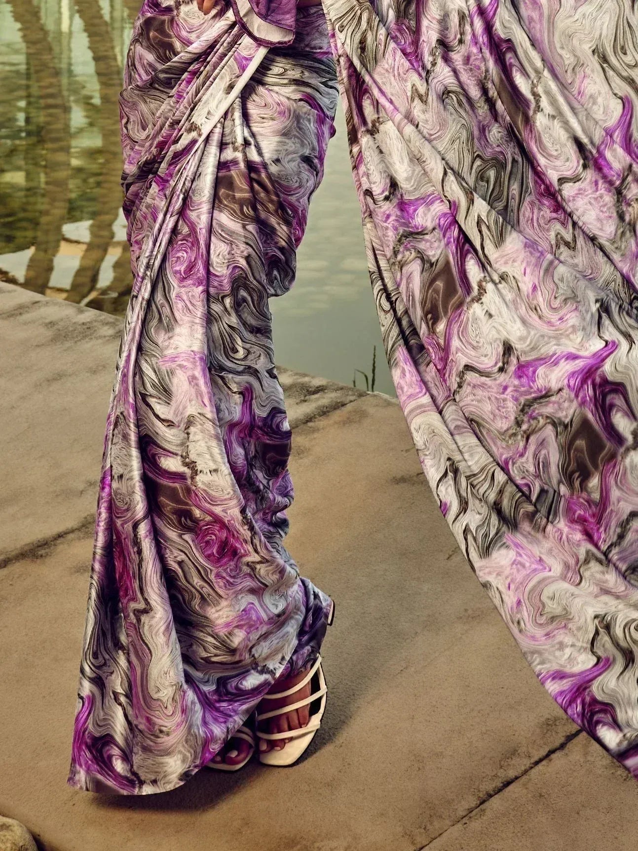 Purple and gray marbled saree with flowing drape, styled with white heels near water