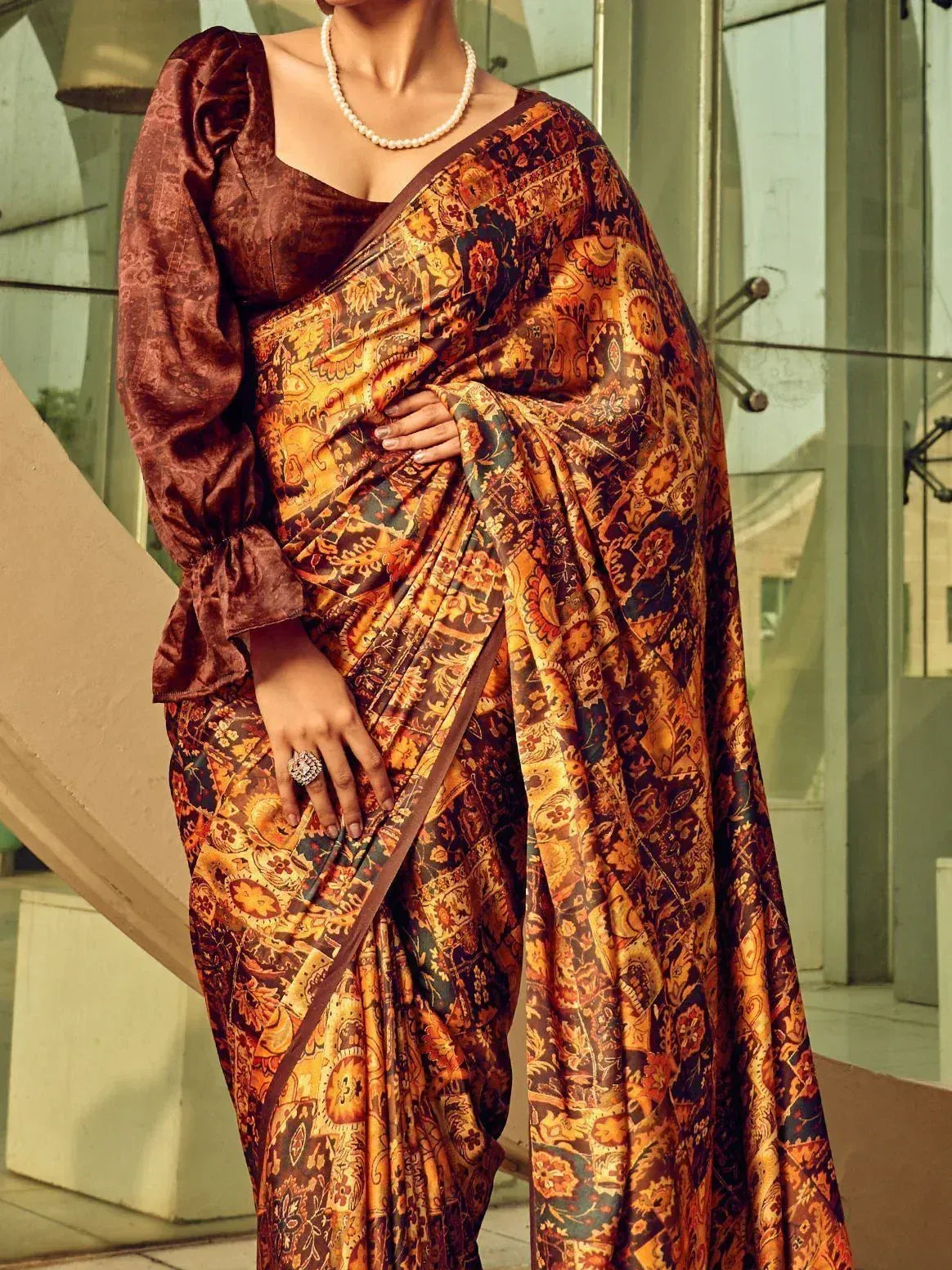 Elegant Indian saree with intricate paisley print, paired with a velvet blouse and pearl necklace