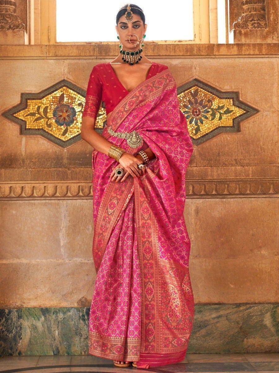 Pink designer saree with gold embroidery, paired with red blouse and traditional jewelry, perfect for Indian ethnic wear.