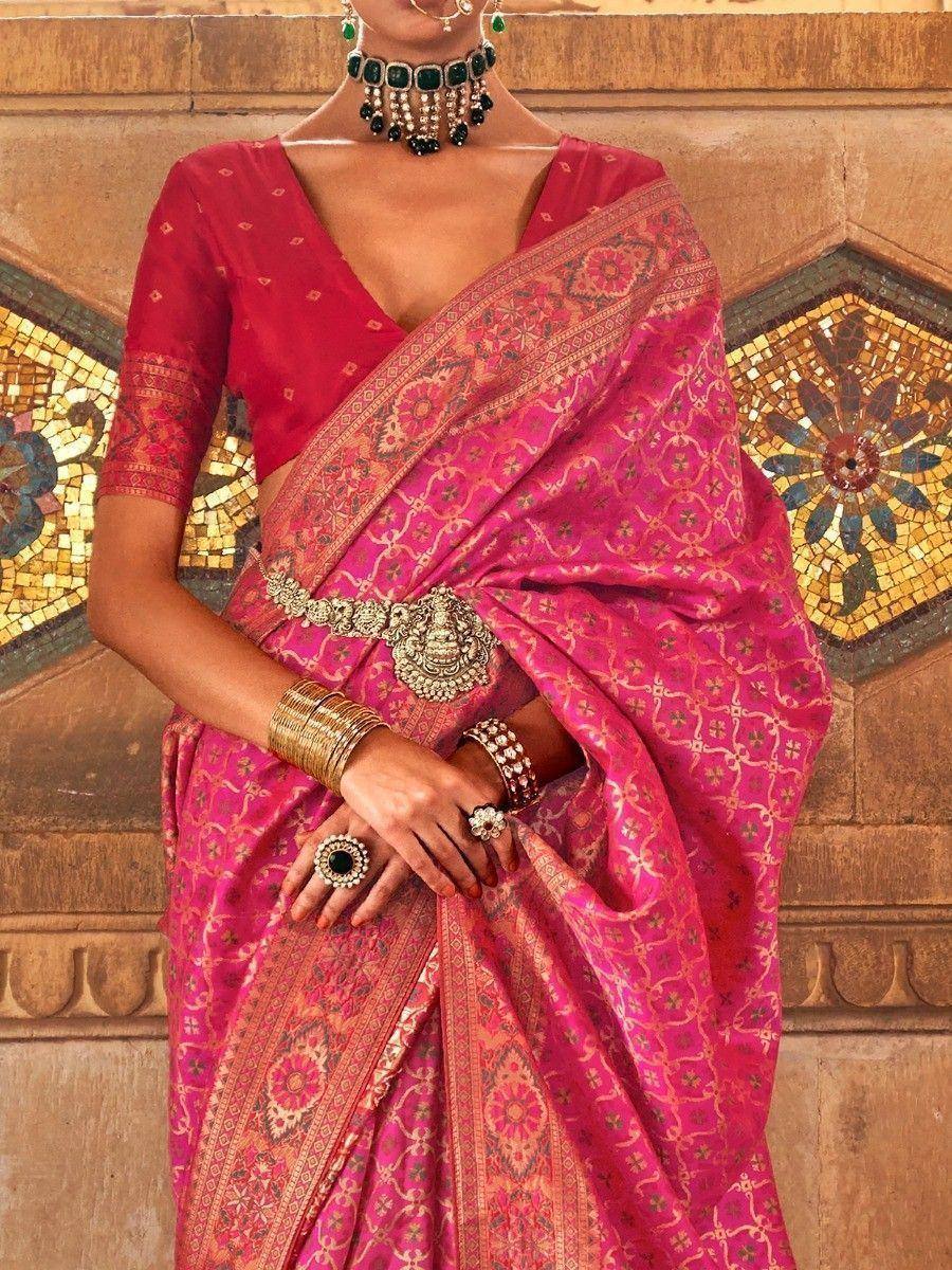 Pink designer saree with gold embroidery, paired with red blouse and traditional jewelry, perfect for ethnic occasions.