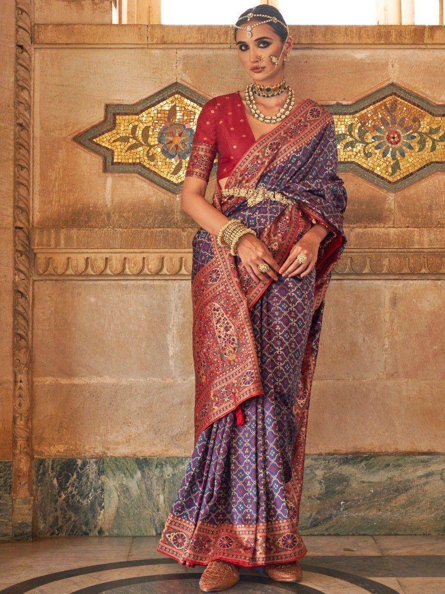 Elegant Indian saree with intricate purple and red patterns, paired with traditional jewelry and blouse.