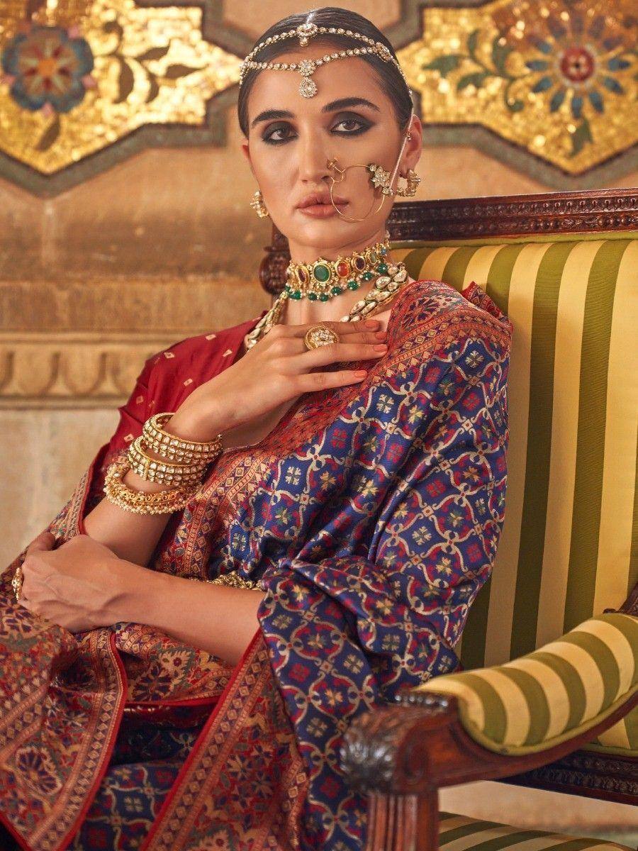 Woman in traditional Indian ethnic wear with intricate jewelry and patterned saree, seated on ornate chair