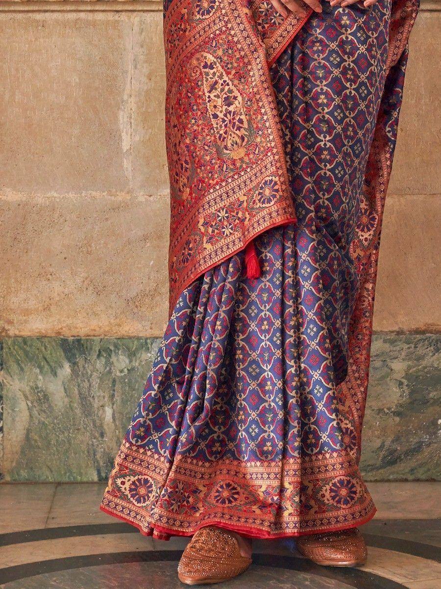 Richly embroidered blue and red Indian saree with gold motifs, paired with traditional juttis, perfect for ethnic occasions.