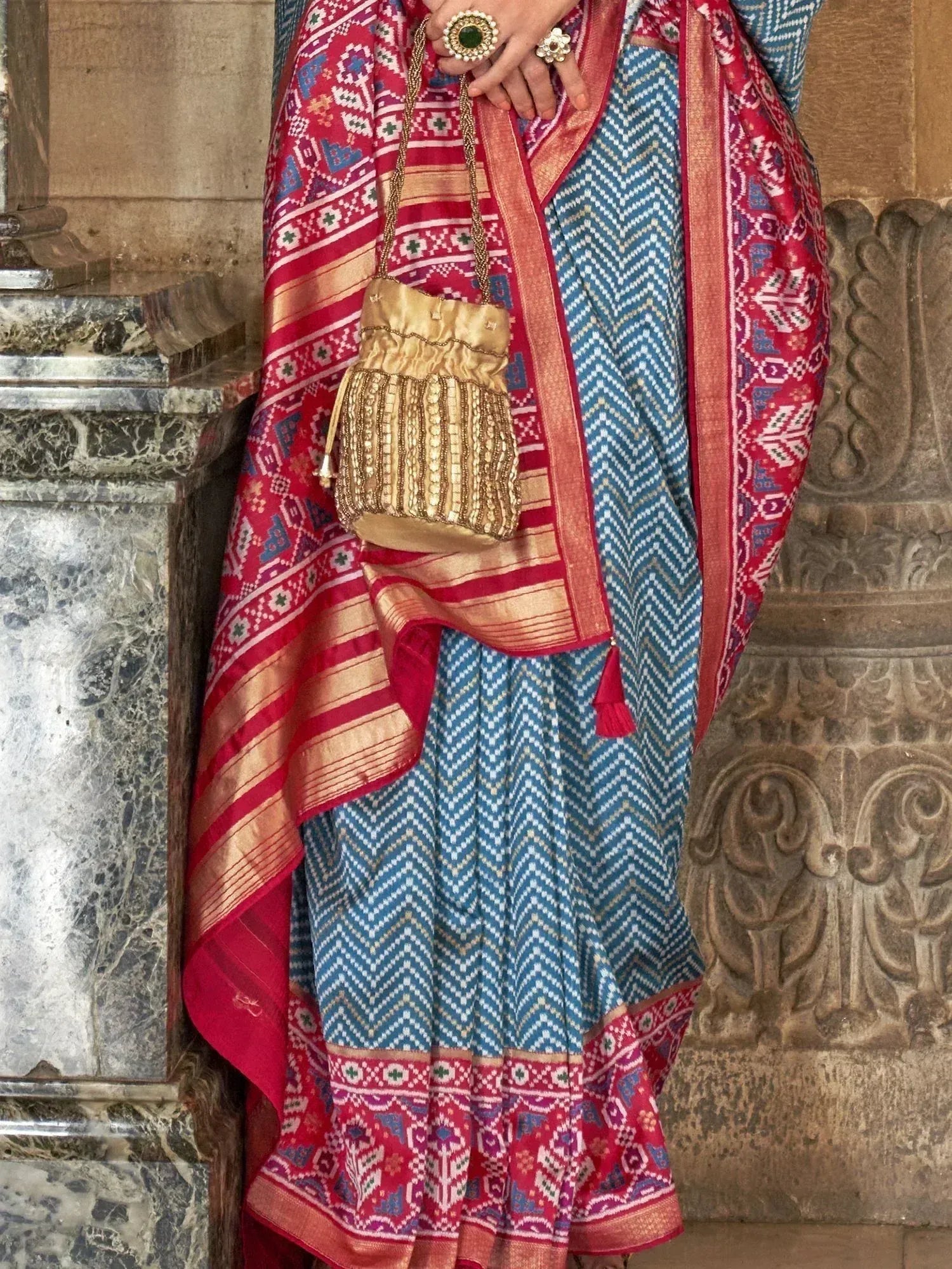 Blue and red ethnic saree with geometric print, gold embellished potli bag, traditional Indian wear