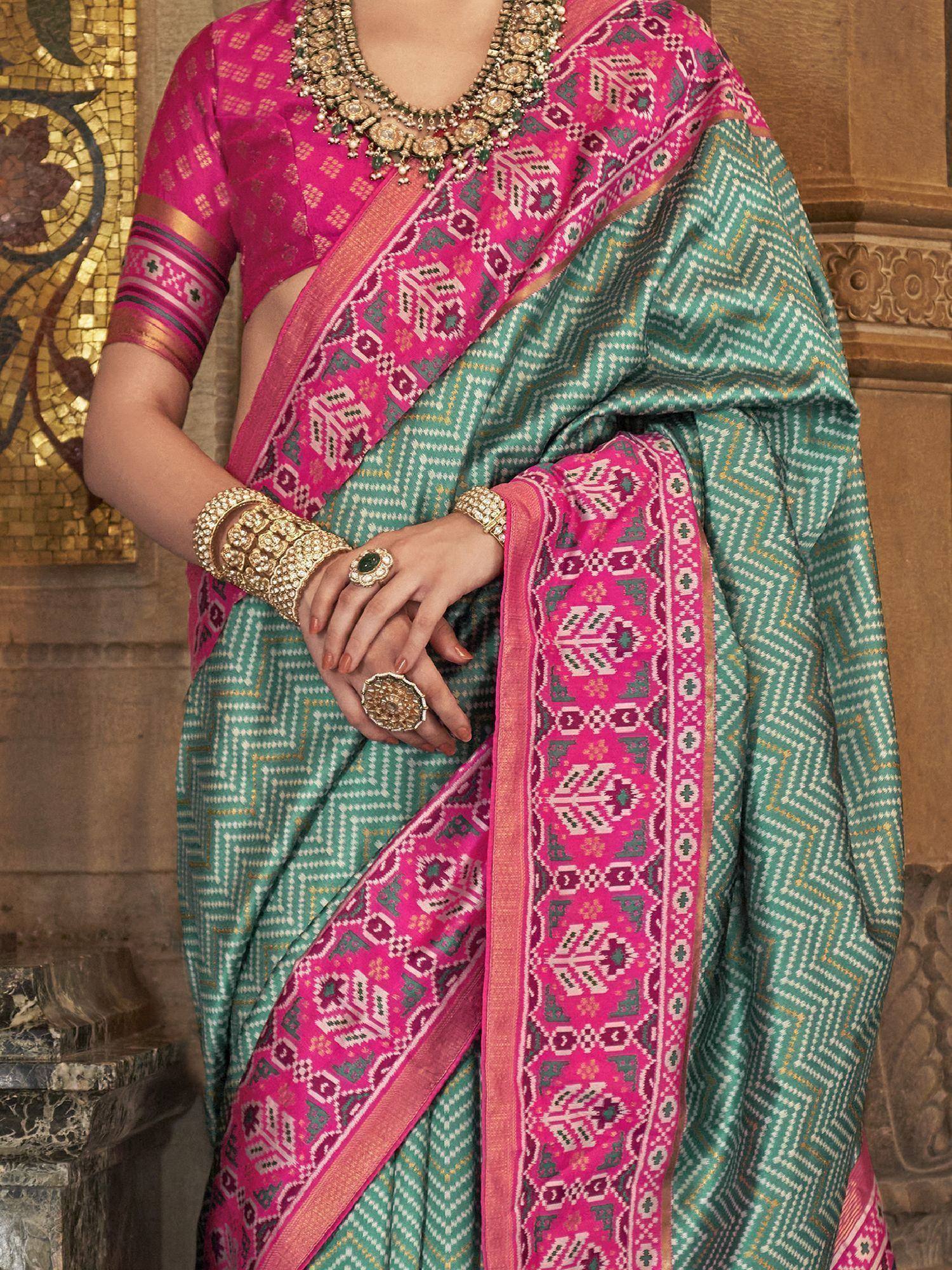 Teal and pink ethnic saree with geometric patterns, paired with gold jewelry for traditional Indian wear