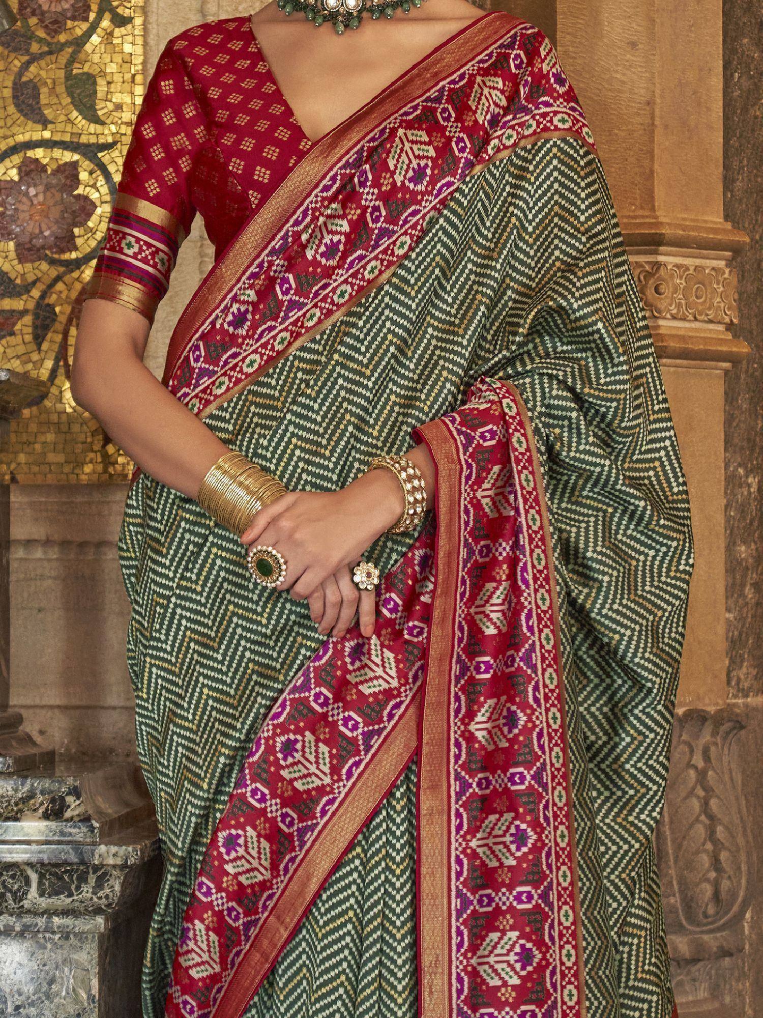 Green and red ethnic saree with geometric patterns, gold border, and traditional jewelry for Indian wear
