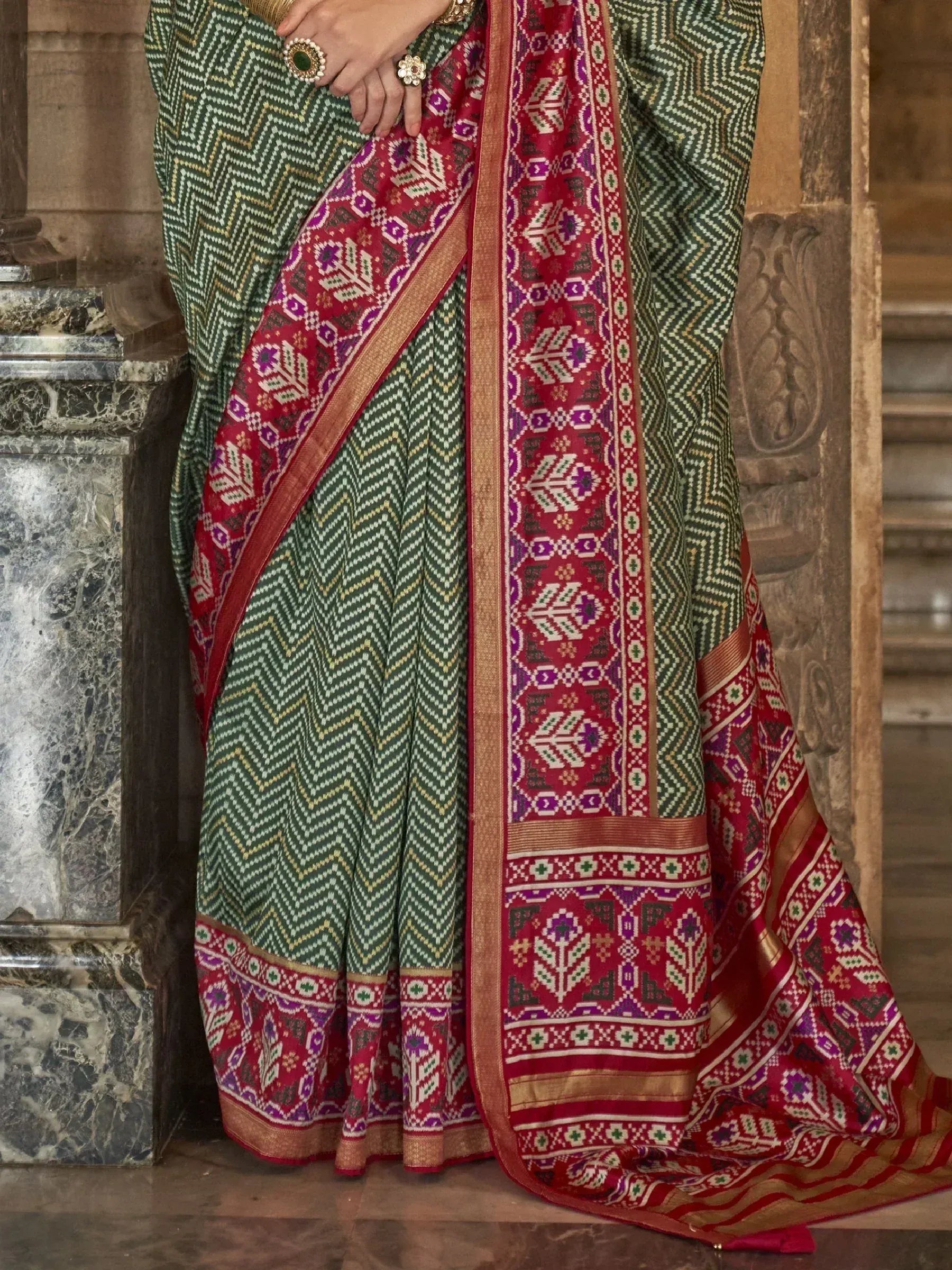 Green and red ethnic saree with geometric patterns and traditional border, styled for Indian occasions