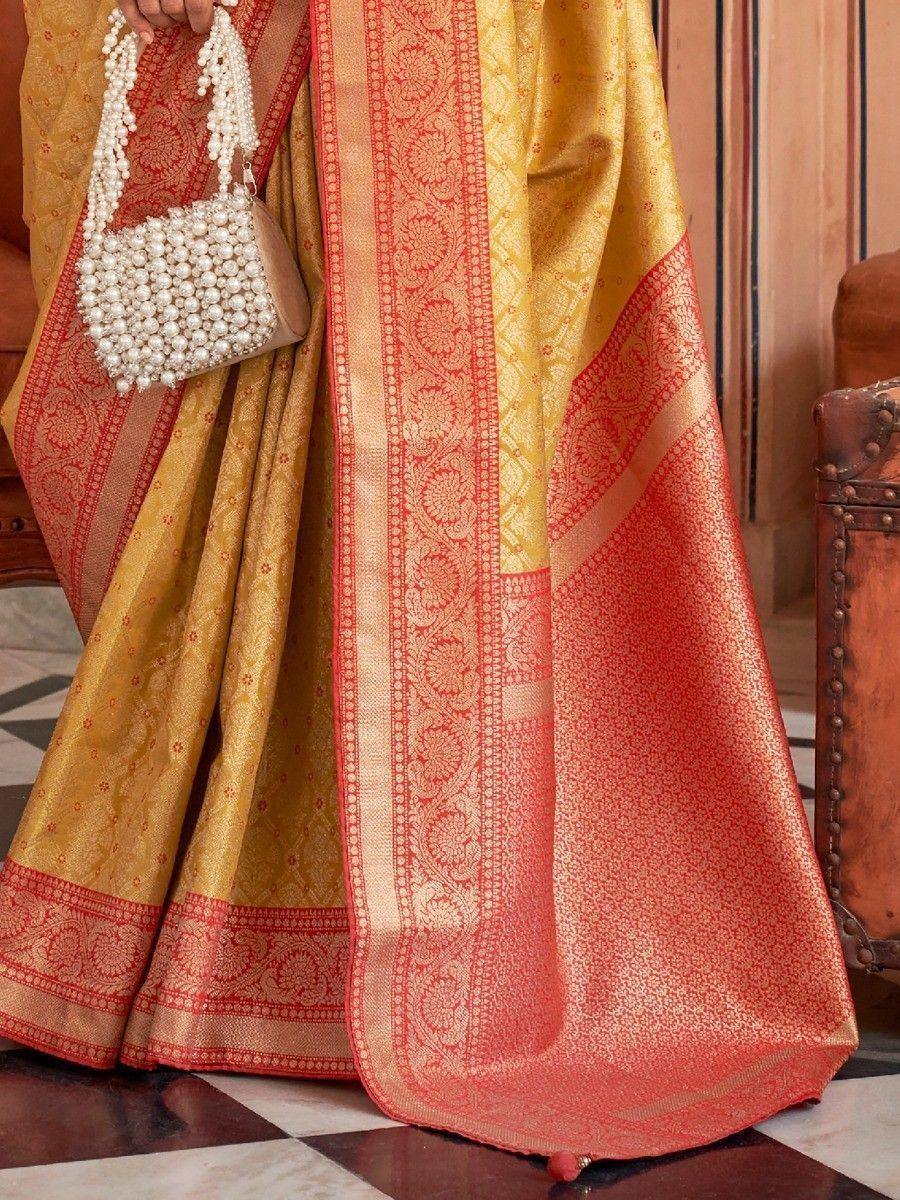 Yellow and red designer saree with intricate gold embroidery and pearl handbag