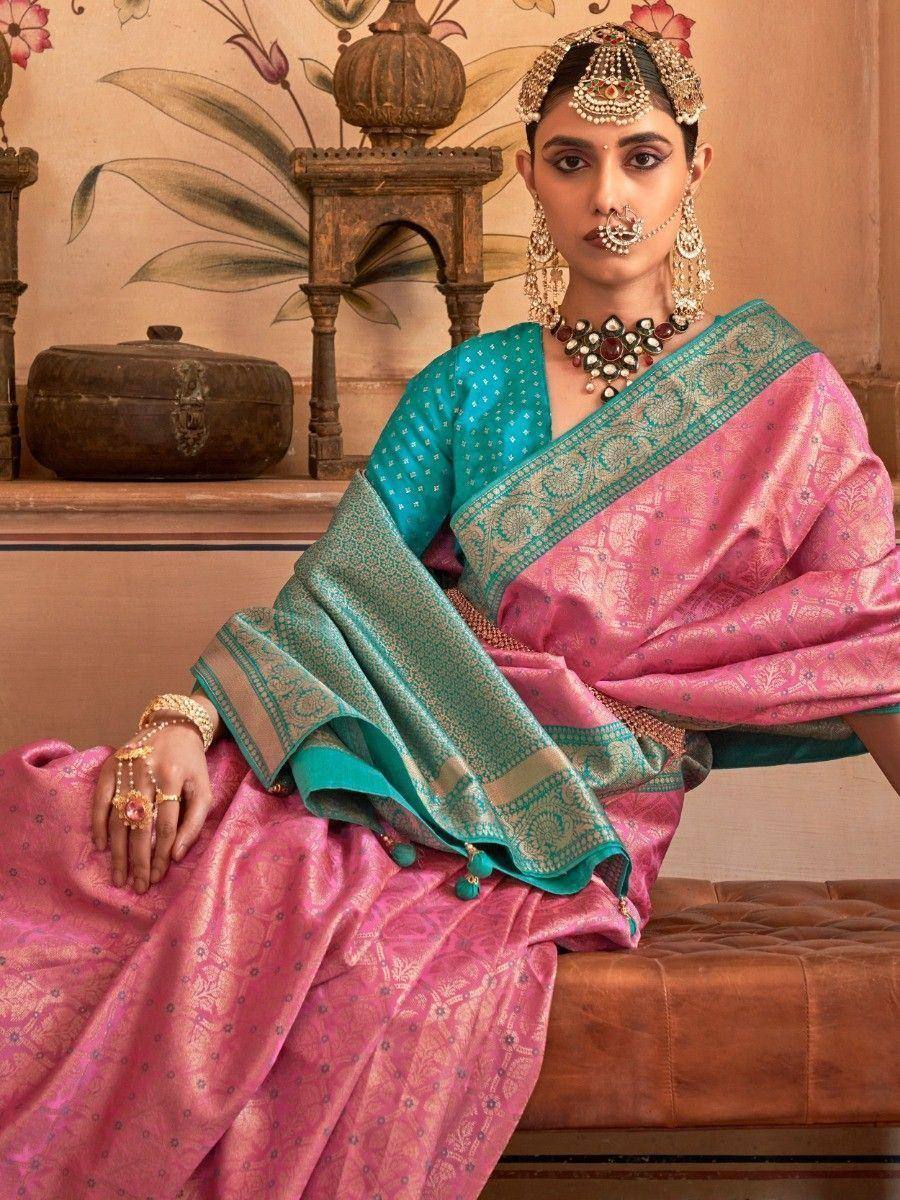 Pink and teal designer saree with intricate embroidery, traditional Indian bridal jewelry, and ethnic styling