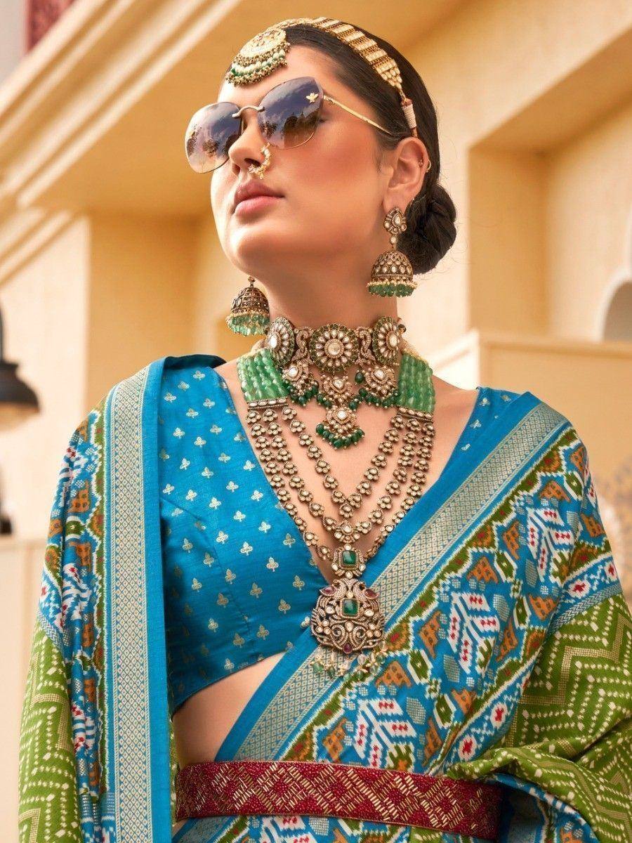 Woman in blue and green printed saree with heavy ethnic jewelry and sunglasses