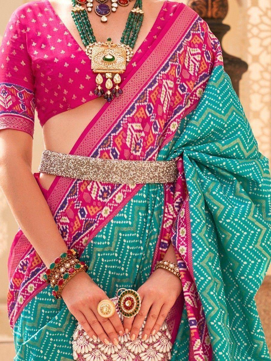 Vibrant pink and teal printed saree with ethnic jewelry and embellished belt for Indian festive wear