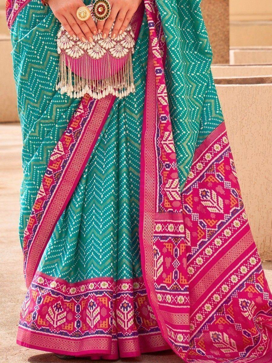 Teal and pink ethnic saree with geometric print and embellished border, styled with matching clutch and rings