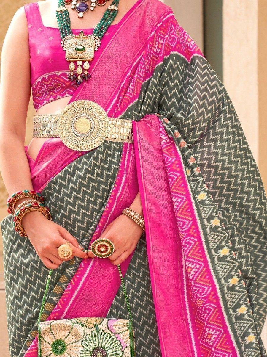Pink and green ethnic saree with intricate patterns and traditional jewelry