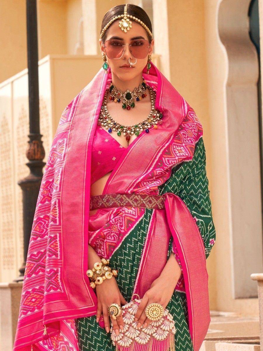Vibrant pink and green ethnic saree with intricate patterns and traditional jewelry