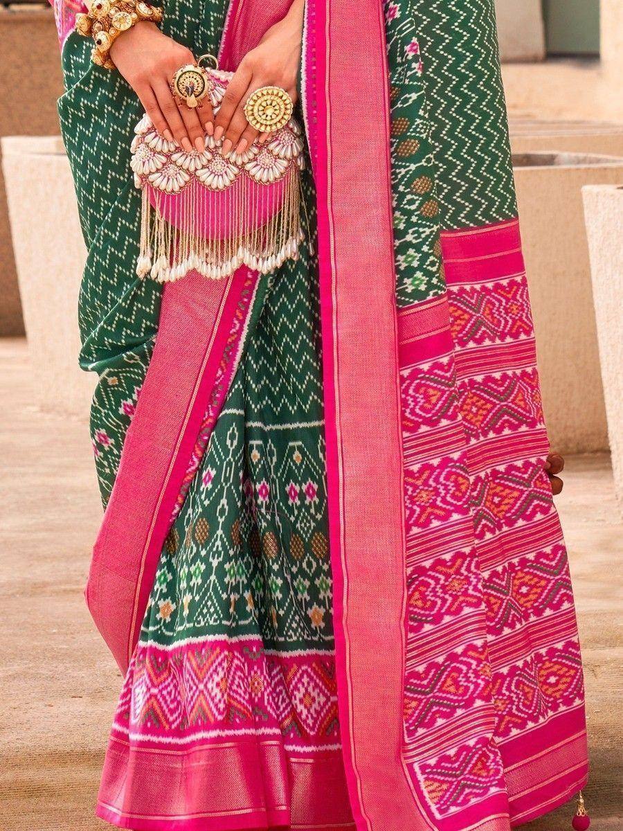 Green and pink ethnic saree with intricate patterns and tassel clutch